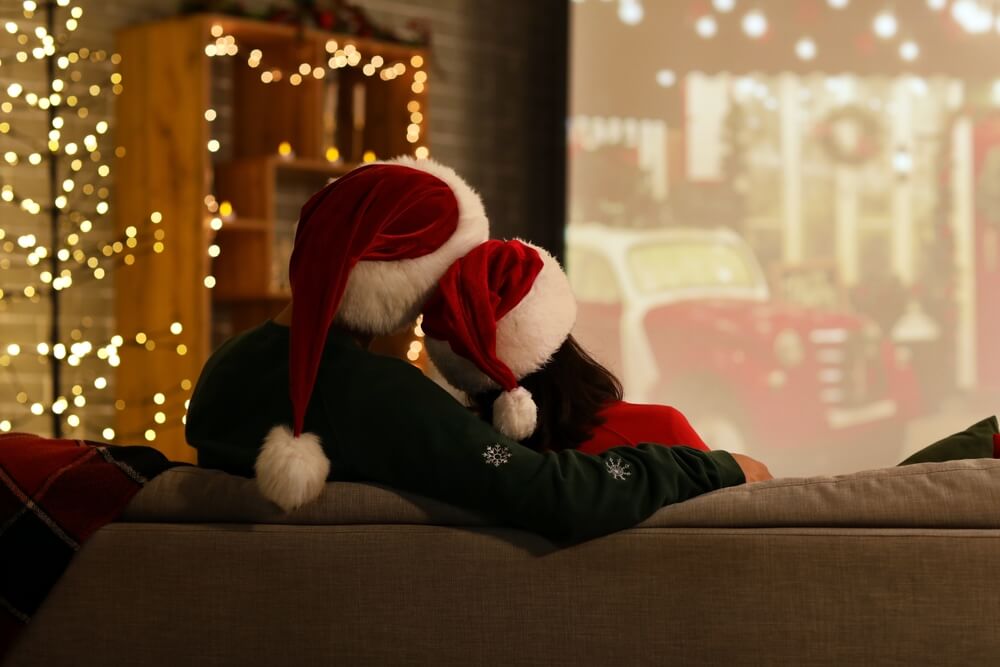 Young,Couple,Watching,Christmas,Movie,On,Projector,Screen,At,Home,